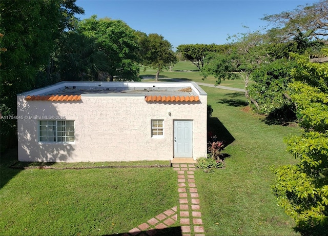 back of property featuring a tiled roof, a yard, and stucco siding