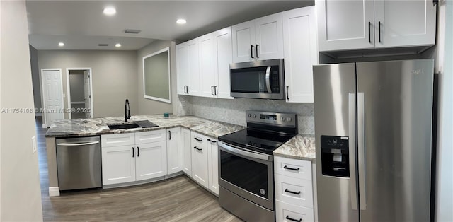 1640 NW 93rd Ave Unit 306, Pembroke Pines, FL 33024 - kitchen with a peninsula, white cabinets, a sink, light wood finished floors, and appliances with stainless steel finishes