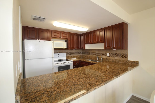 kitchen featuring white appliances, visible vents, a sink, and a peninsula