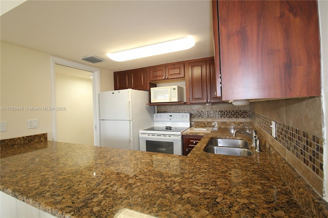 kitchen with a peninsula, white appliances, visible vents, and a sink