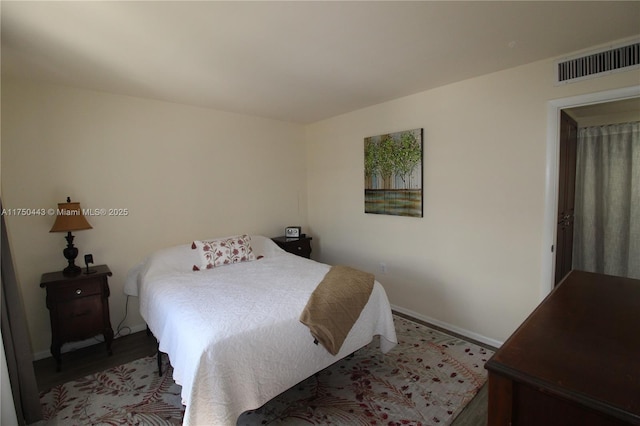 bedroom featuring baseboards, visible vents, and wood finished floors