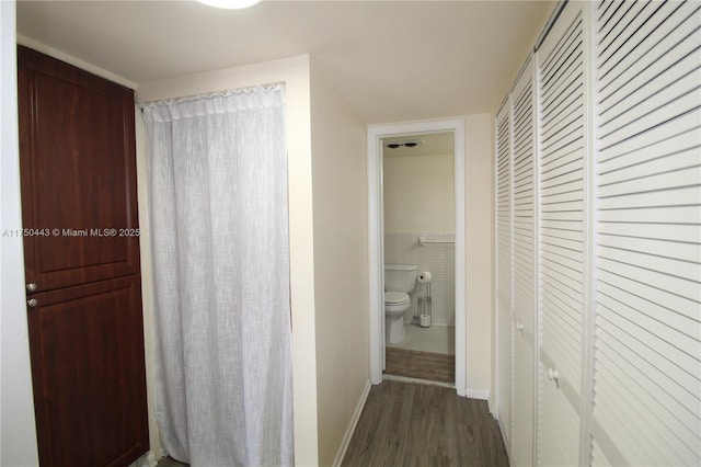 hallway featuring baseboards, tile walls, and dark wood-type flooring