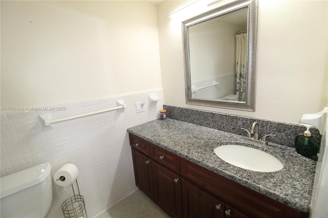 full bathroom featuring tile walls, a wainscoted wall, vanity, and toilet