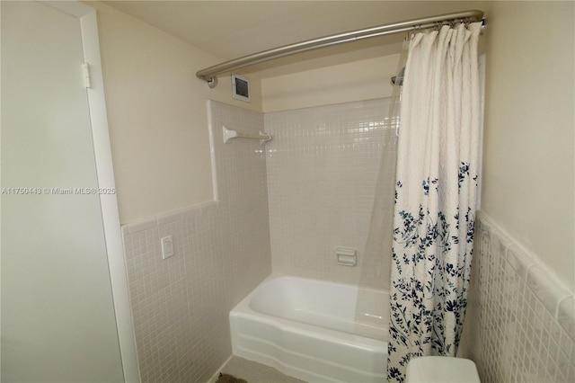 full bathroom featuring a wainscoted wall, visible vents, tile walls, and shower / bath combo with shower curtain