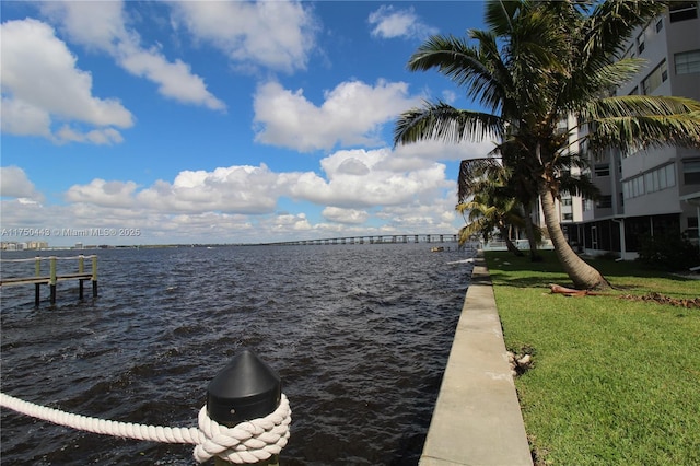 view of dock with a water view and a lawn