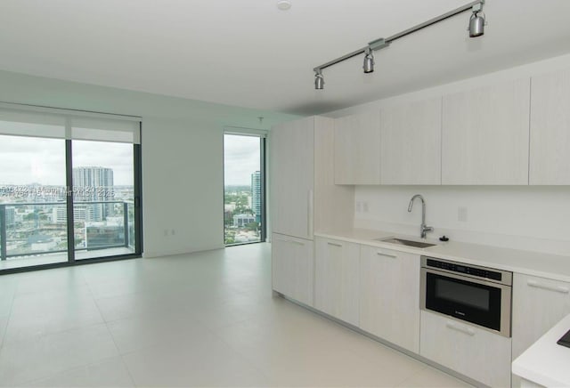 kitchen featuring light countertops, a healthy amount of sunlight, stainless steel oven, and a sink