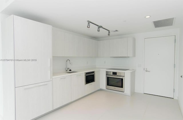 kitchen featuring visible vents, black electric stovetop, a sink, and oven