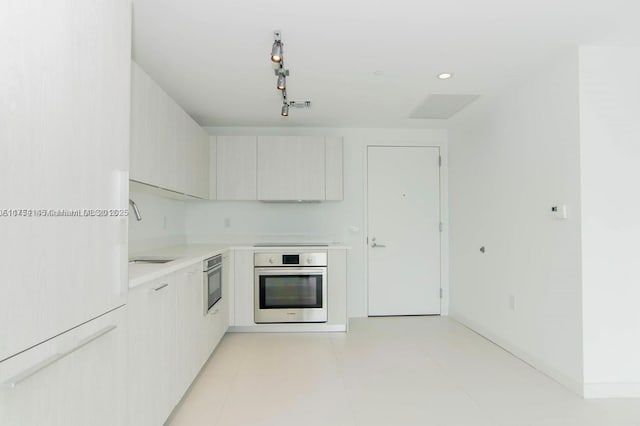 kitchen with light countertops, modern cabinets, a sink, and oven