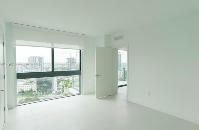 spare room featuring a city view, visible vents, and baseboards