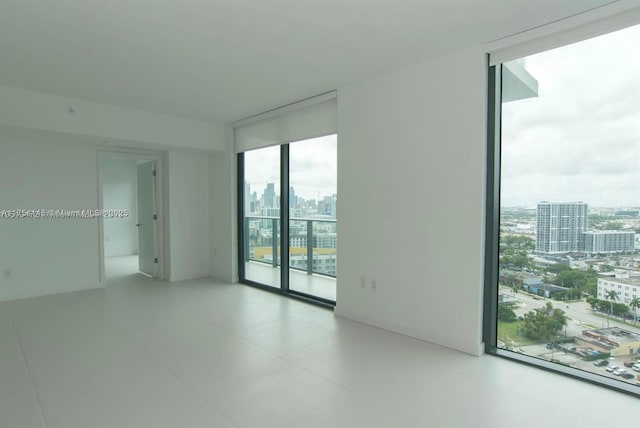 empty room featuring floor to ceiling windows, a healthy amount of sunlight, and a city view