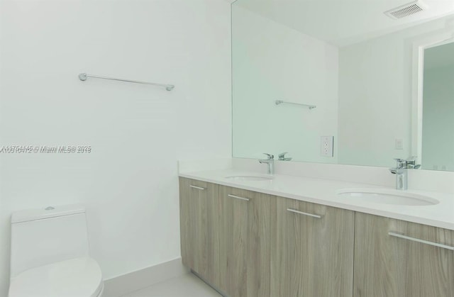 bathroom featuring visible vents, a sink, toilet, and double vanity