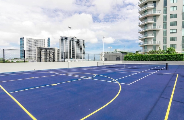 view of sport court featuring a view of city and fence