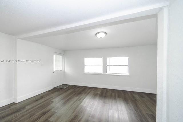 spare room with dark wood-style flooring and baseboards