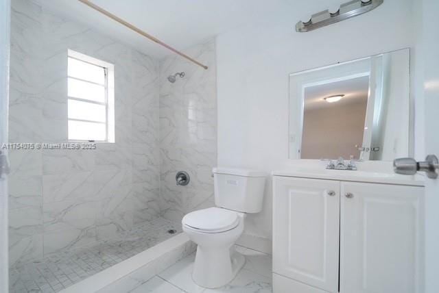 bathroom featuring toilet, marble finish floor, a marble finish shower, and vanity