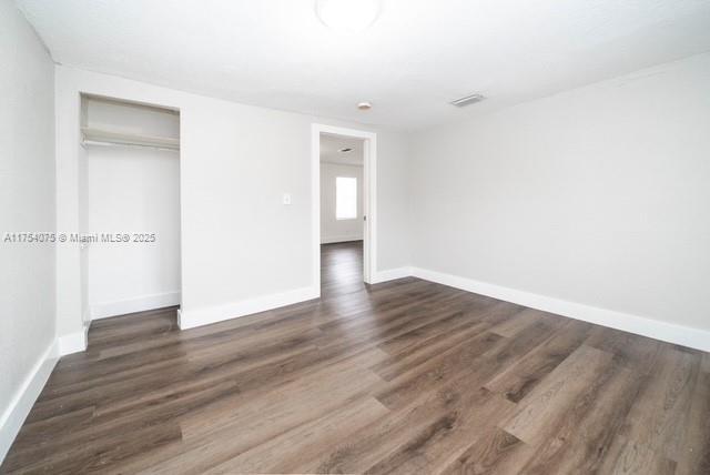 unfurnished bedroom featuring a closet, baseboards, and wood finished floors