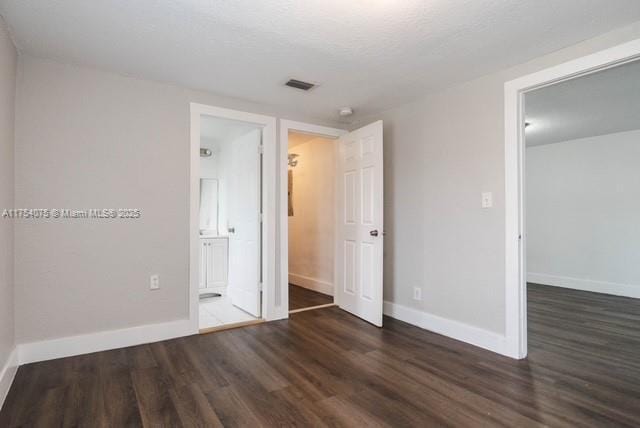 unfurnished bedroom with visible vents, baseboards, and wood finished floors