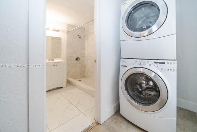 washroom with marble finish floor, laundry area, and stacked washer / dryer