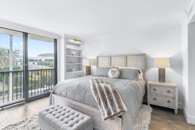 bedroom with visible vents, ornamental molding, wood finished floors, access to outside, and baseboards