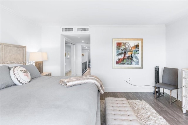 bedroom featuring baseboards, wood finished floors, visible vents, and crown molding