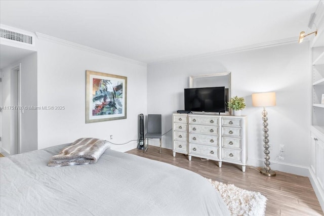 bedroom with visible vents, crown molding, baseboards, and wood finished floors