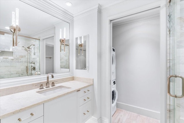 full bath with a stall shower, stacked washer and clothes dryer, crown molding, and wood finished floors