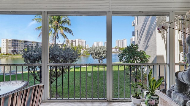 sunroom featuring a view of city, a water view, and a wealth of natural light