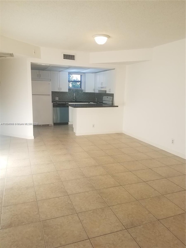 kitchen with dark countertops, visible vents, decorative backsplash, freestanding refrigerator, and dishwasher