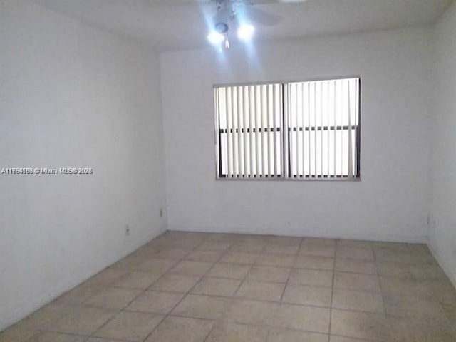 tiled spare room featuring ceiling fan