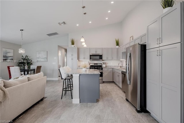 kitchen with stainless steel appliances, open floor plan, visible vents, and a kitchen bar