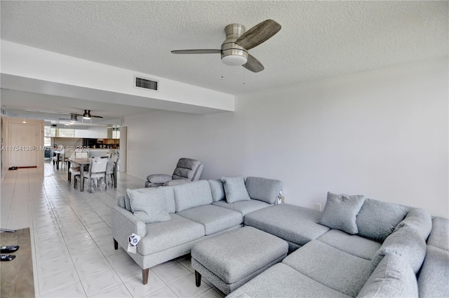 living room with visible vents, ceiling fan, and a textured ceiling