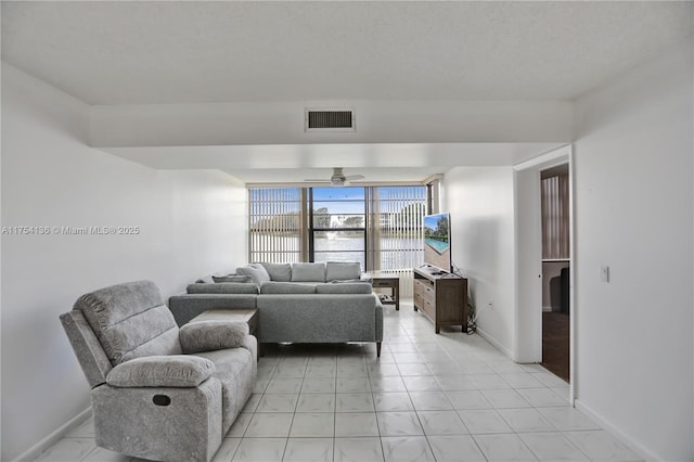 living area featuring baseboards, visible vents, and a ceiling fan