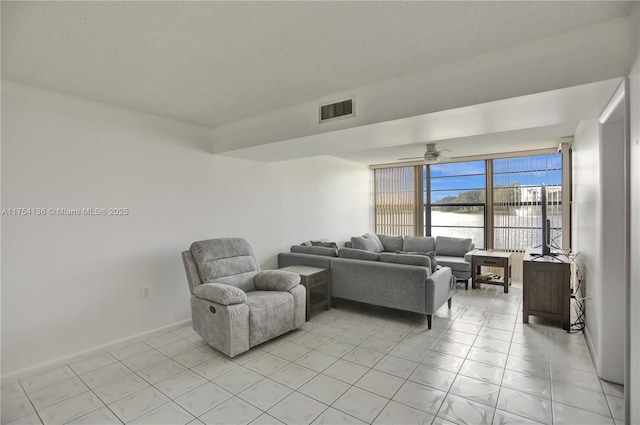 living area featuring baseboards, visible vents, and a ceiling fan