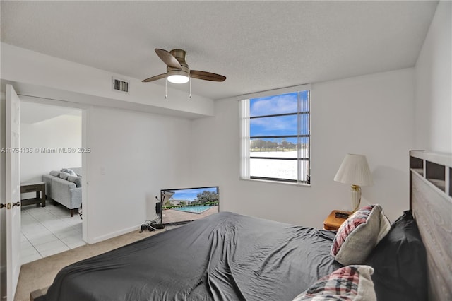 carpeted bedroom featuring baseboards, ceiling fan, visible vents, and a textured ceiling