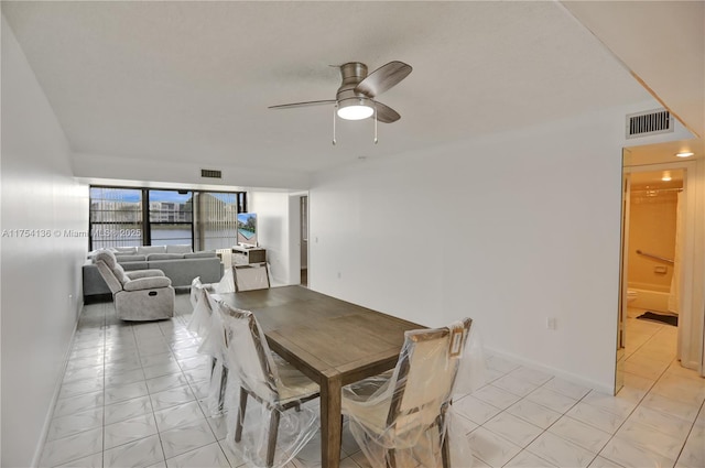 dining area featuring visible vents, light tile patterned flooring, a ceiling fan, and baseboards