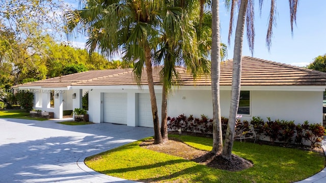 view of front facade featuring a garage, driveway, a front yard, and stucco siding