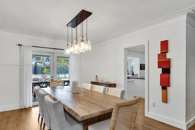 dining room featuring baseboards, light wood-type flooring, and crown molding