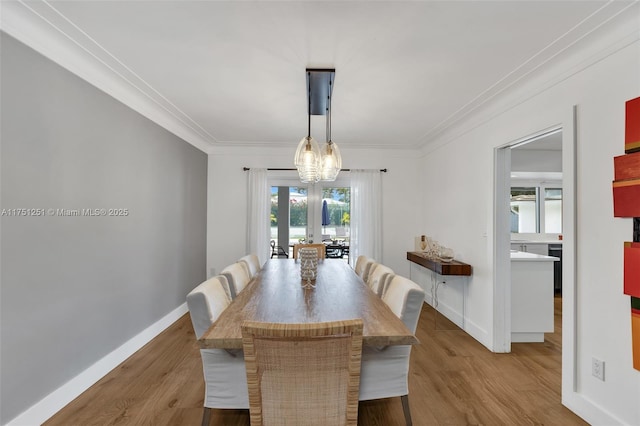 dining room featuring a notable chandelier, ornamental molding, wood finished floors, and baseboards