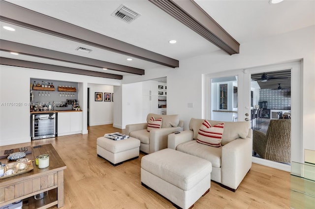 living area with a dry bar, visible vents, wine cooler, beamed ceiling, and light wood-type flooring