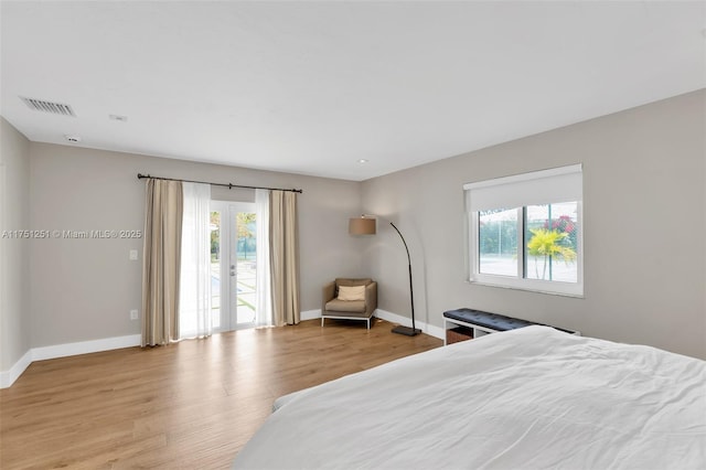 bedroom with baseboards, multiple windows, visible vents, and wood finished floors