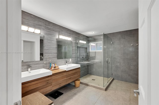 full bathroom featuring a stall shower, a sink, tile walls, and tile patterned floors