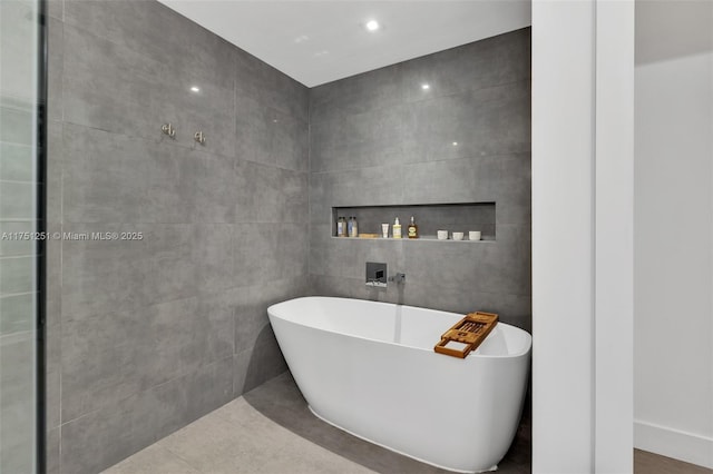 bathroom featuring a soaking tub, tile patterned flooring, and tile walls