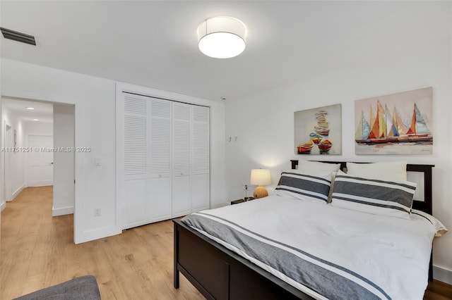 bedroom with light wood-style floors, a closet, visible vents, and baseboards