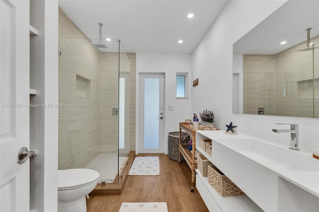 full bath featuring vanity, a shower stall, toilet, and wood finished floors