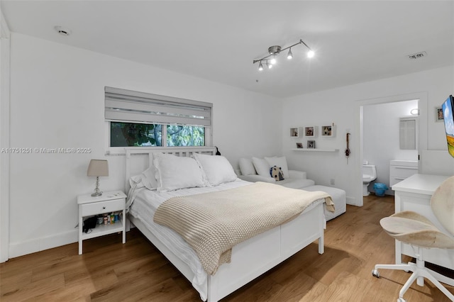 bedroom featuring wood finished floors, visible vents, and baseboards