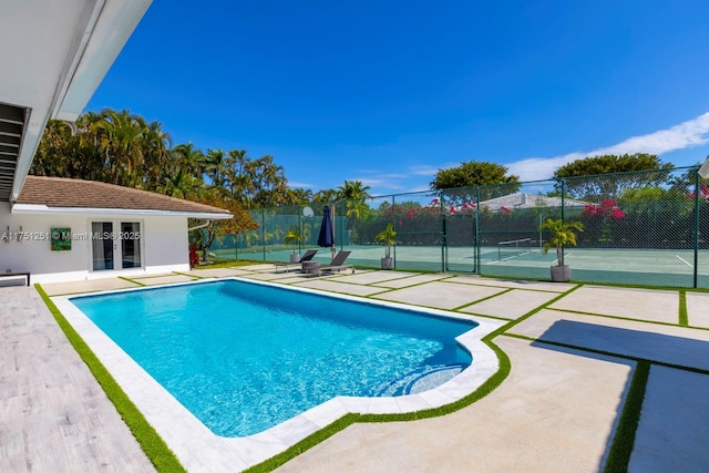 view of swimming pool with a tennis court, a patio area, fence, and a fenced in pool