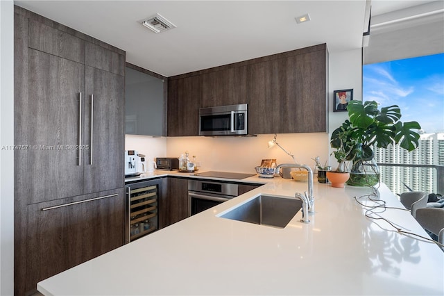 kitchen featuring appliances with stainless steel finishes, wine cooler, modern cabinets, and a sink