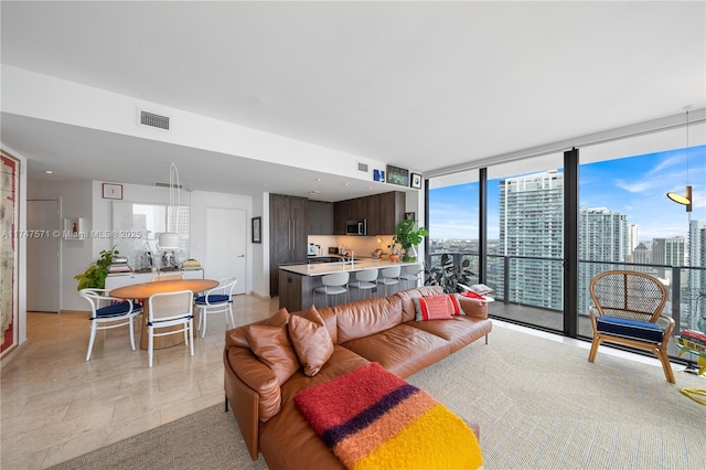 living room with a view of city, visible vents, and floor to ceiling windows