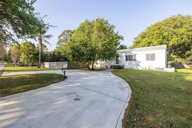 view of front of house with stucco siding, entry steps, fence, concrete driveway, and a front yard