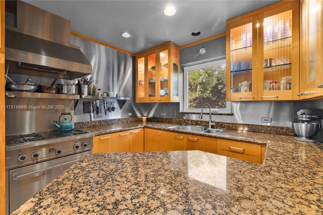 kitchen featuring a sink, wall chimney range hood, dark stone counters, and stainless steel range