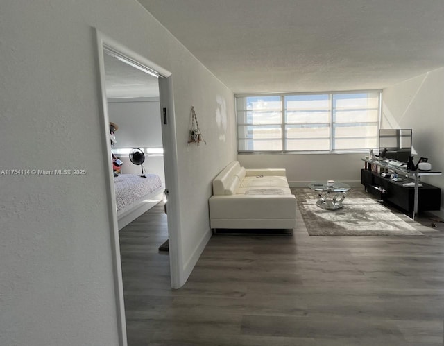 living area with a textured ceiling, baseboards, and wood finished floors